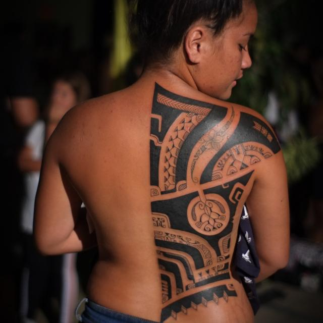 A person displaying traditional Marquesan tattoos on their back.